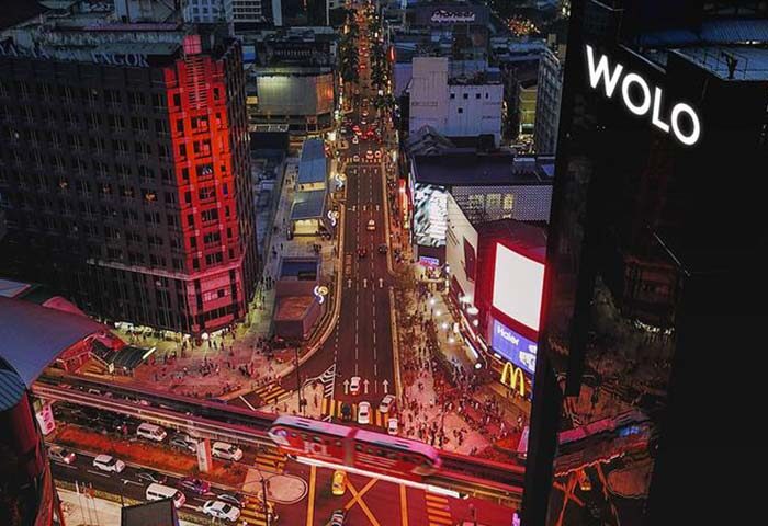 Night view of WOLO Kuala Lumpur, a gay-friendly hotel. Cityscape with busy streets, train, McDonald's, and bright lights. Great for gay travel.
