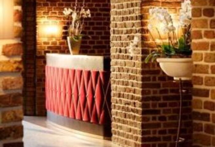 Interior of Wasserturm Hotel Cologne, a gay-friendly Curio Collection by Hilton. Brick walls and a red reception desk with flower decorations.