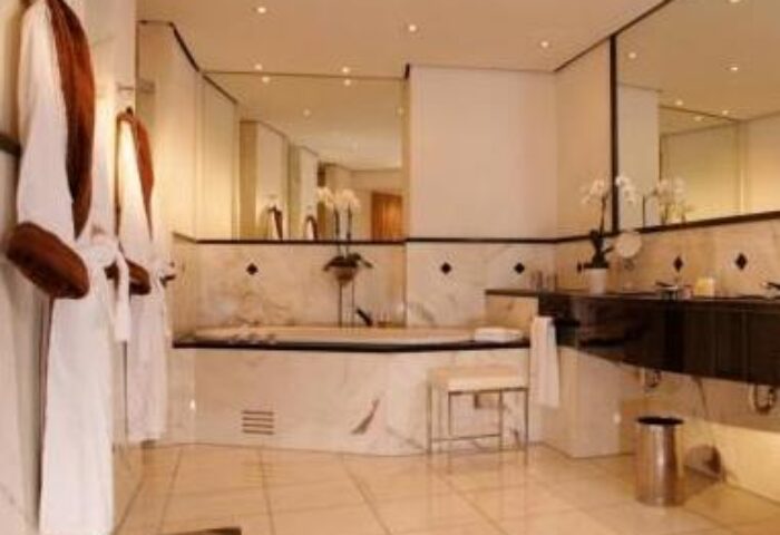 Bathroom at Wasserturm Hotel Cologne, a gay-friendly Curio Collection by Hilton. Features a bathtub, robes, and modern design.