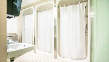 West Side YMCA Hostel showers. Interior of a gay-friendly hotel bathroom with shower stalls and a sink. Budget travel for gay men.