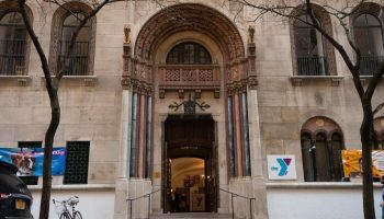 West Side YMCA Hostel, a gay-friendly hotel. Building's entrance with arched doorway, steps, & YMCA logo. Great for gay travel.