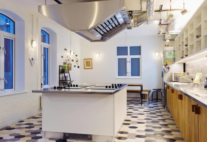 Wombats City Hostel London's kitchen. Modern design, stainless steel island, and unique hexagonal floor tiles. Gay-friendly hotel for travelers.