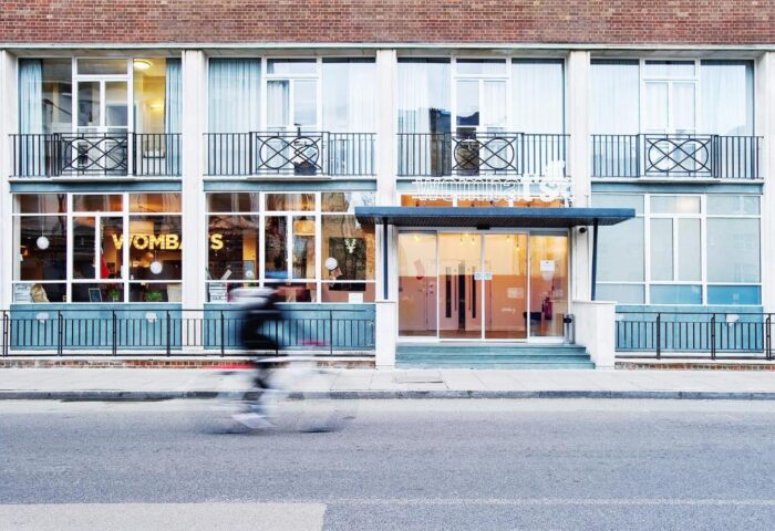 Wombats City Hostel London exterior. Gay-friendly hotel with modern facade. Cyclist passing by. Great for gay men travel in London.