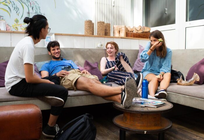 Guests relax at Wombats City Hostel Munich, a gay-friendly hotel. People lounge on a sofa, enjoying a friendly atmosphere.