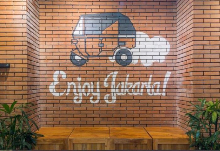 Wonderloft Hostel, gay-friendly hotel in Jakarta. Brick wall with Enjoy Jakarta! graffiti and vehicle drawing. Great for gay travelers.