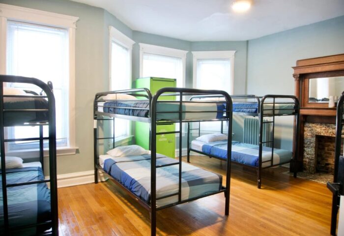 Dorm room at Wrigley Hostel, an adults-only, gay-friendly hotel. Bunk beds, hardwood floors, and a green locker provide budget accommodations.