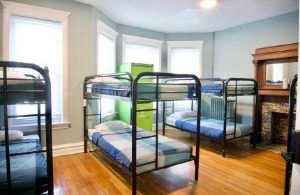 Dorm room at Wrigley Hostel, an adults-only, gay-friendly hotel. Bunk beds, hardwood floors, and a green locker provide budget accommodations.