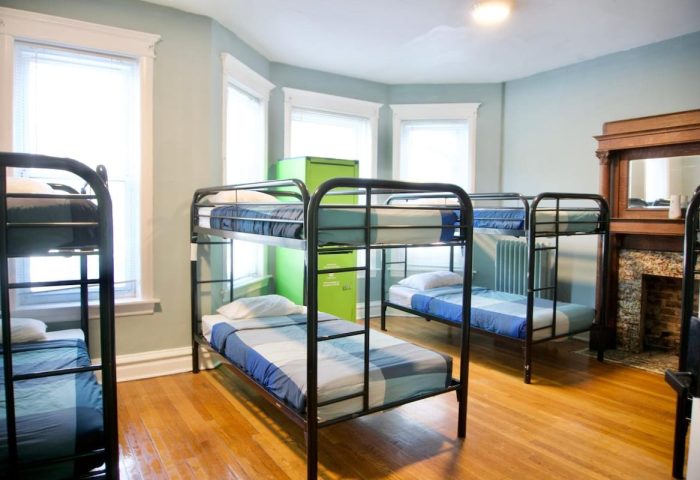 Dorm room at Wrigley Hostel, an adults-only, gay-friendly hotel. Bunk beds, hardwood floors, and a green locker provide budget accommodations.