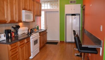 Kitchen at Wrigley Hostel, a gay-friendly adults-only hotel. Features include a stove, microwave, fridge, sink, and breakfast bar.