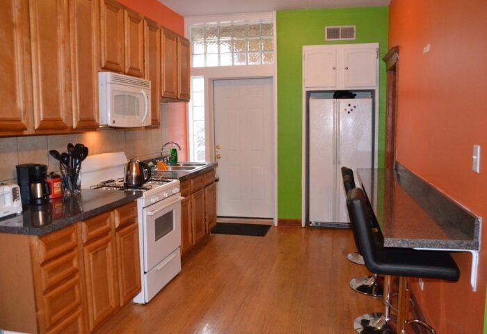 Kitchen at Wrigley Hostel, a gay-friendly adults-only hotel. Features include a stove, microwave, fridge, sink, and breakfast bar.