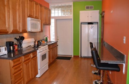 Kitchen at Wrigley Hostel, a gay-friendly adults-only hotel. Features include a stove, microwave, fridge, sink, and breakfast bar.