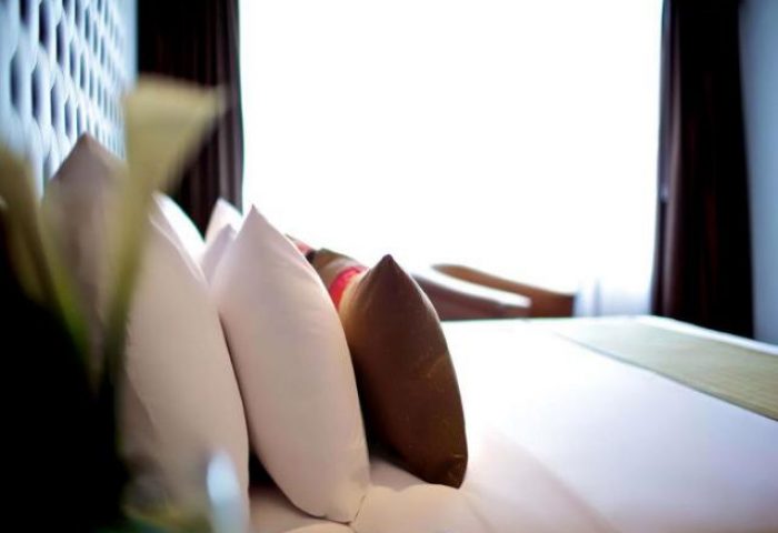 Wyndham Casablanca Jakarta gay-friendly hotel bedroom. Pillows on a bed with a bright window. Comfortable stay for gay travelers.