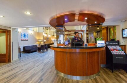 XO Hotels City Centre's reception area. A staff member is at the desk. Gay-friendly hotel with a modern, welcoming lobby.