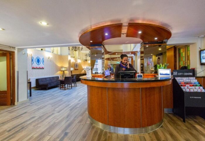 XO Hotels City Centre's reception area. A staff member is at the desk. Gay-friendly hotel with a modern, welcoming lobby.