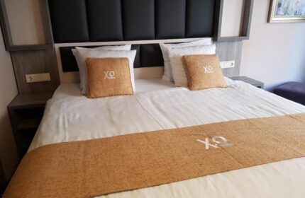 XO Hotels City Centre room. Gay-friendly hotel with a double bed, headboard, pillows, and a decorative runner. Modern design for gay travelers.
