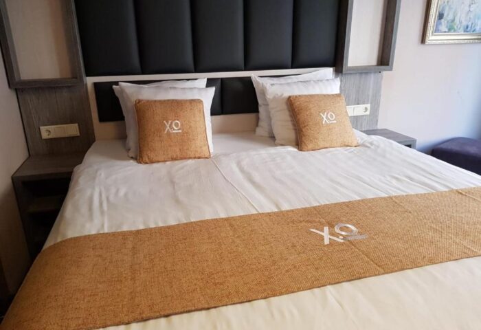 XO Hotels City Centre room. Gay-friendly hotel with a double bed, headboard, pillows, and a decorative runner. Modern design for gay travelers.