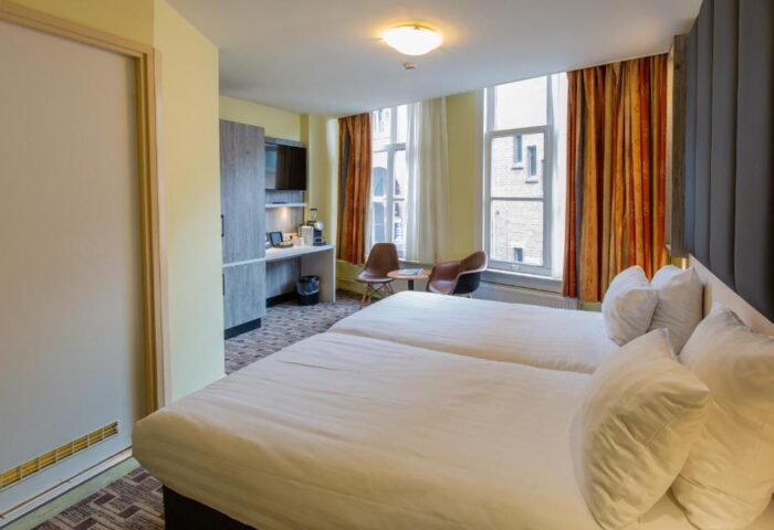 XO Hotels City Centre gay-friendly room with twin beds, desk, chairs, and city views. Comfortable stay for gay travelers in Amsterdam.