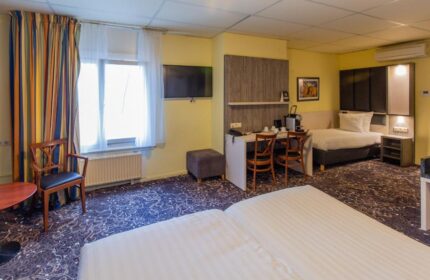 XO Hotels City Centre gay-friendly room. Twin beds, desk, chairs, TV, and window with curtains. Comfortable stay in Amsterdam.