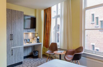 XO Hotels City Centre gay-friendly room. Features a desk, TV, coffee maker, and seating area. A comfortable stay in Amsterdam's heart.