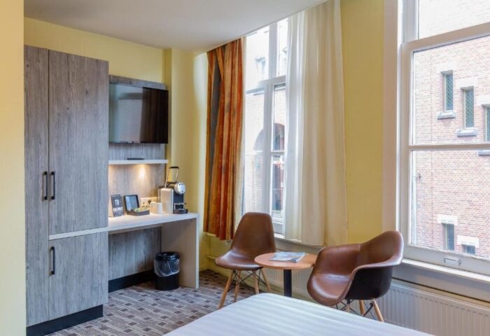 XO Hotels City Centre gay-friendly room. Features a desk, TV, coffee maker, and seating area. A comfortable stay in Amsterdam's heart.