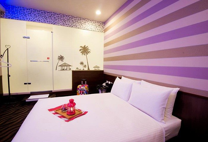 Ximen Holiday Fun Hotel room. Gay-friendly hotel with queen bed, striped wall, and tropical themed decor. Great for gay travel in Ximending, Taipei.