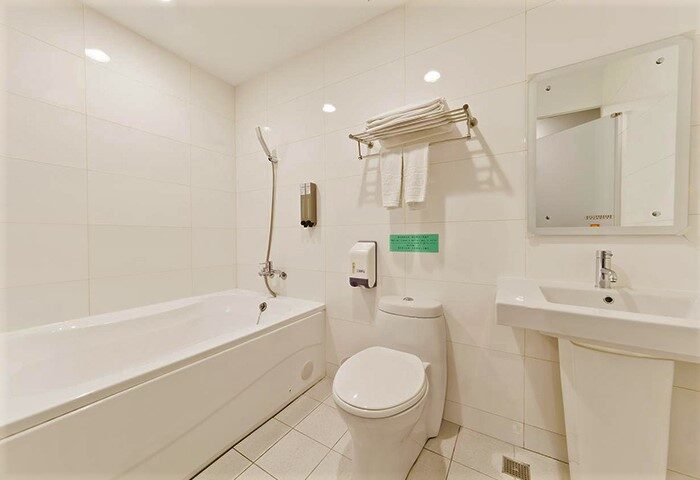 Bathroom at Ximen Holiday Fun Hotel, a gay-friendly hotel. Features a tub, toilet, sink, mirror, and white tile. Clean and modern design.