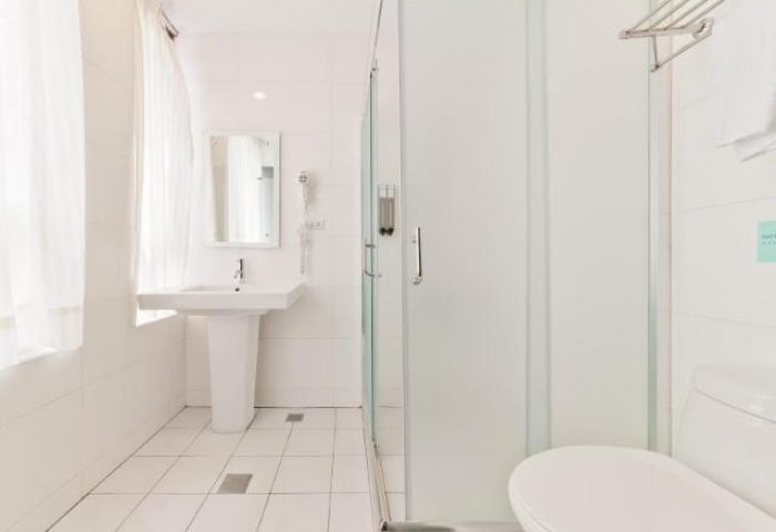 Bathroom at Ximen Holiday Fun Hotel, a gay-friendly hotel. Features a white toilet, shower, sink, mirror, and white tile floor. Modern design.