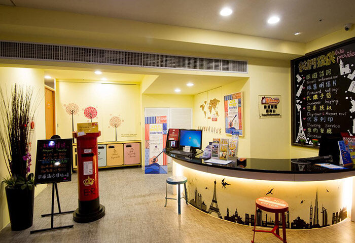 Ximen Holiday Fun Hotel's gay-friendly lobby. Features a stylish reception desk with city skyline art, travel info, and a red British postbox.