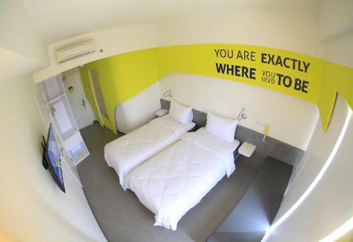 YELLO Hotel Manggarai room. Gay-friendly hotel with twin beds, yellow accent wall, and modern design. Perfect for gay men travel in Jakarta.
