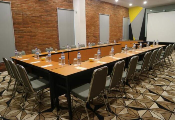 YELLO Hotel Manggarai meeting room setup. Long tables with chairs, water bottles, and glasses. Gay-friendly hotel for events.