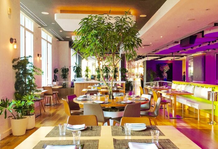 YOTEL New York Times Square restaurant. Gay-friendly hotel with modern decor, tables set, and indoor plants. Great for gay travelers.