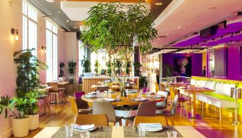YOTEL New York Times Square restaurant. Gay-friendly hotel with modern decor, tables set, and indoor plants. Great for gay travelers.
