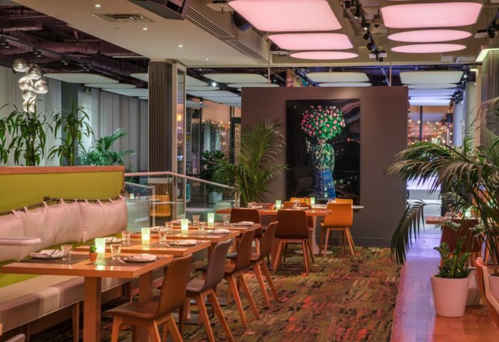 YOTEL New York Times Square interior. Gay-friendly hotel restaurant with tables, chairs, plants, and modern decor. Upscale dining.