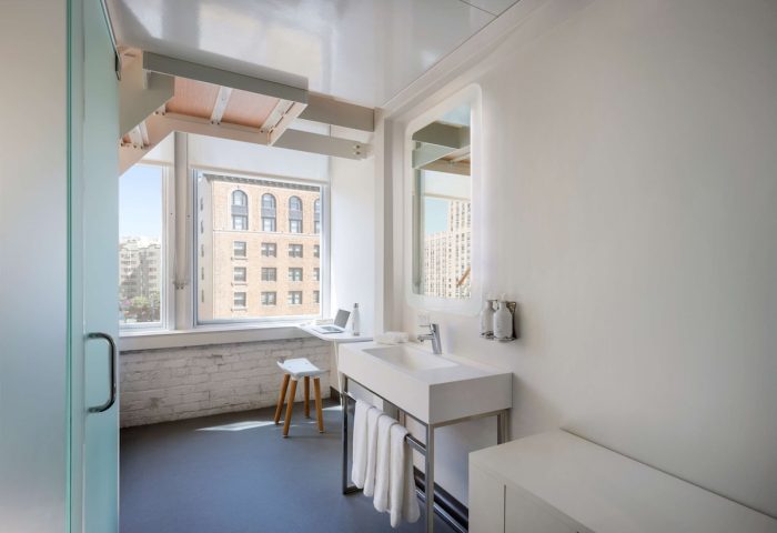 YOTEL San Francisco bathroom view. Modern design, white fixtures, window view, and a laptop. Gay-friendly hotel for travelers.