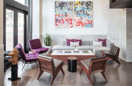 YOTEL San Francisco lobby seating area. Gay-friendly hotel with modern design, purple chairs, and abstract art. Perfect for gay travelers.
