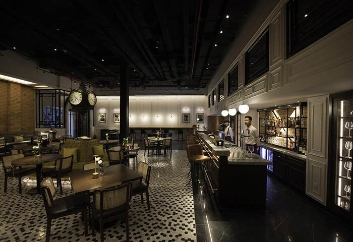 Yangon Excelsior's bar area, a gay-friendly hotel. The bar has tables, chairs, and a counter with bartenders. Perfect for gay men travel advice.