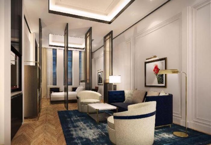 Yangon Excelsior gay-friendly hotel room. Living area with blue rug, sofa, chairs, and art. Bedroom with bed visible through room dividers.