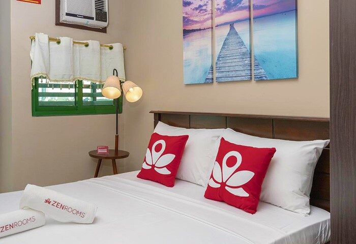 ZEN Rooms Symphony Timog Ave QC gay-friendly hotel room. Bed with red pillows, ZENRooms towels. Comfortable stay in Quezon City.