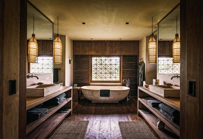 Bathroom at Zannier Hotels Phum Baitang. Gay-friendly hotel with a tub, sinks, and wooden accents. Luxury travel for gay men.