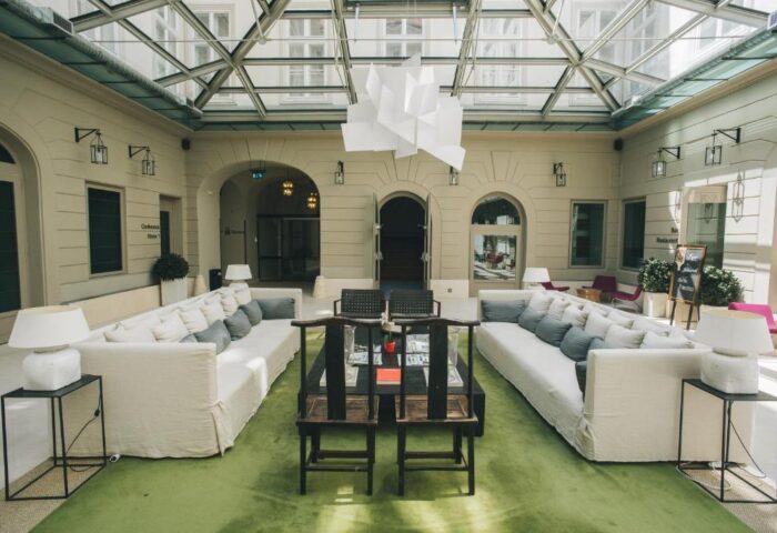 Zenit Budapest Palace hotel lobby with glass ceiling. Gay-friendly hotel in Budapest, Hungary. Modern design, sofas, and lounge area.