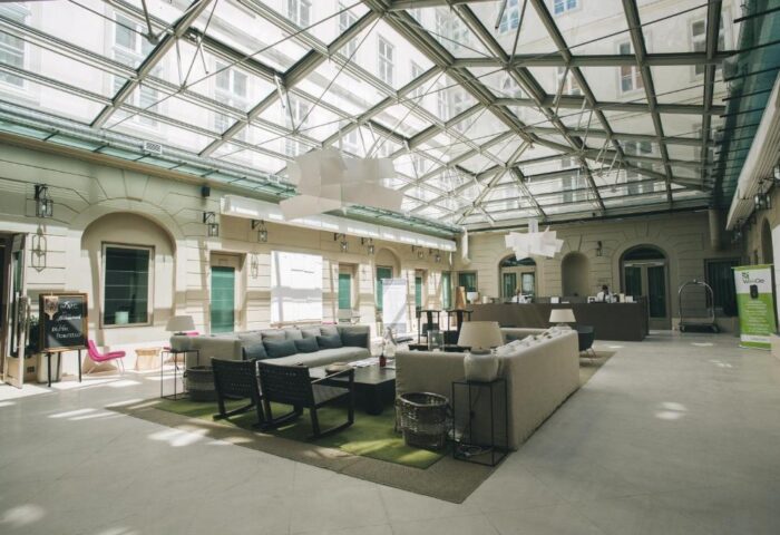 Zenit Budapest Palace lobby with glass ceiling. Gay-friendly hotel interior with sofas, chairs, and reception desk. A great choice for gay travel.