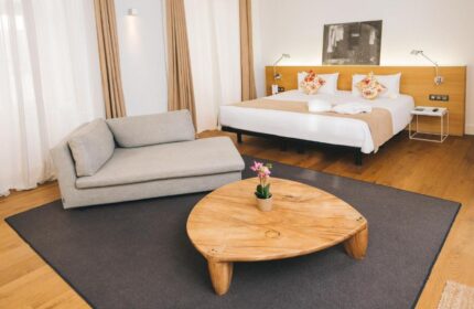 Zenit Budapest Palace gay-friendly hotel room. Modern interior with bed, couch, wooden table, and stylish decor. Ideal for gay travel in Budapest.