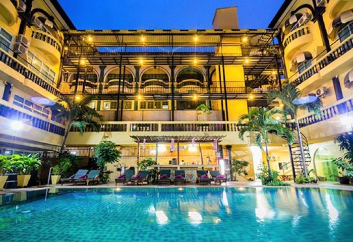 Zing Resort & Spa pool view, gay-friendly hotel. Tropical palm trees, lounge chairs, and bar area. Ideal for gay travel and relaxation.