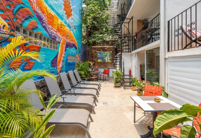 ZonaZ Boutique Hotel's gay-friendly courtyard. Loungers, tables, and a colorful mural create a relaxing vibe for gay travelers.