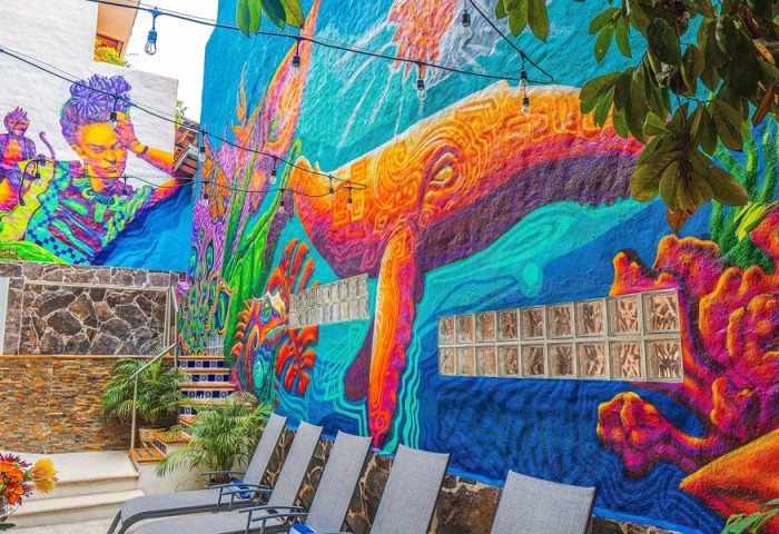 ZonaZ Boutique Hotel's gay-friendly vibe: vibrant mural featuring Frida Kahlo and a whale. Loungers invite relaxation in this colorful hotel.