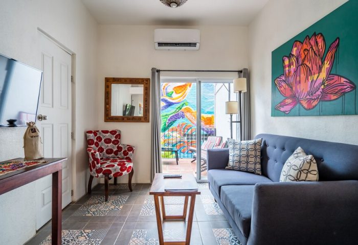 ZonaZ Boutique Hotel gay-friendly room. Living area with blue sofa, colorful art, and balcony view. Stylish gay hotel for gay travel.