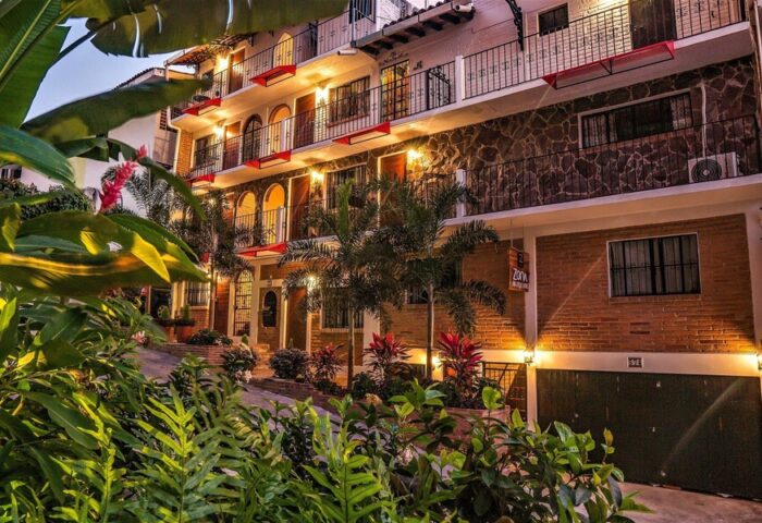 ZonaZ Boutique Hotel, a gay-friendly hotel. Exterior view of the hotel with plants, balconies, and warm lighting. Gay travel advice.