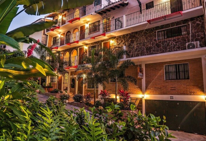 ZonaZ Boutique Hotel, a gay-friendly hotel. Exterior view of the hotel with plants, balconies, and warm lighting. Gay travel advice.