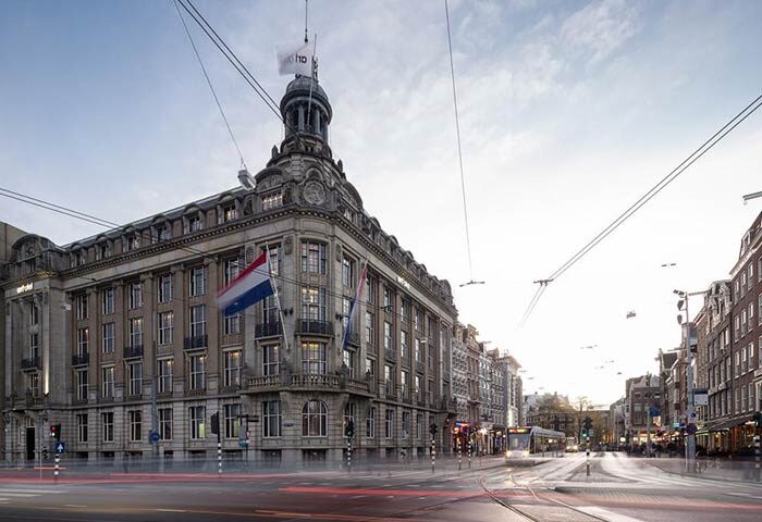 art'otel Amsterdam, a gay-friendly hotel. Exterior view of the hotel with Dutch flags and city street. Amsterdam travel advice.