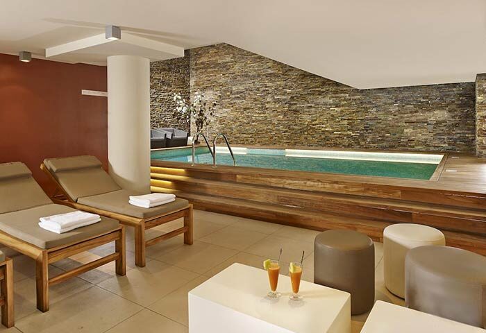 art'otel Amsterdam gay-friendly hotel pool. Indoor pool with lounge chairs, drinks, and stone wall. Gay travel advice in Amsterdam.